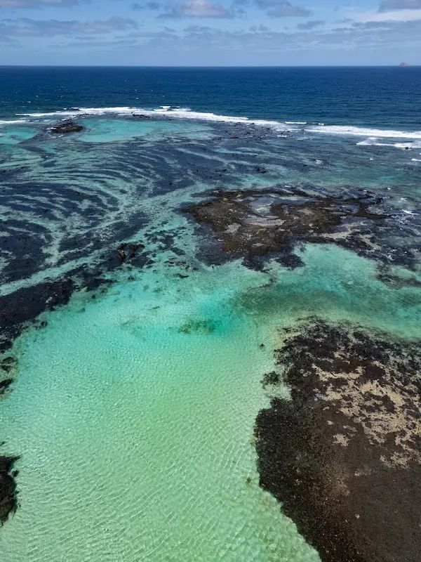 Vista aérea de piscinas naturales con aguas turquesas y roca volcánica en la costa de Lanzarote